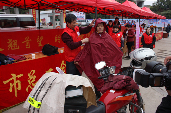 梧州市總工會的黨員義工們在市東出口春運服務站助力“摩托大軍”平安返鄉(xiāng)，幫助他們檢查車輛和行李，穿上雨衣。--黃賀峰攝.j